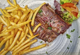 A large steak frites plate, featuring a well-seared skirt steak piled next to a generous portion of