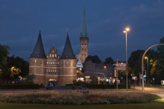 LUBECK, GERMANY - AUGUST 3, 2016: Holstentor Gate and st Jakob church during twilight. Lubeck is