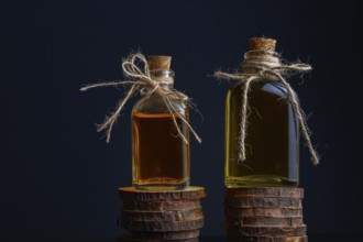 Close-up of two glass bottles with cork stopper and raffia string with rosemary oil and rose oil on