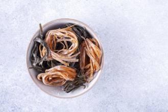 Pasta with carrots and spinach in a round plate on a light textured background, top view, space for