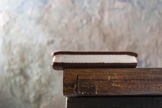 Ice cream sandwich with plombir and chocolate chip cookies on the edge of the table, copy space