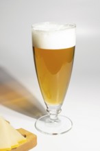 Glass of beer and cheese board on white background