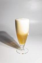 A drop of beer flows down a glass on a white background, copy space