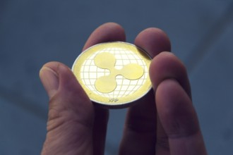 Silver gold ripple coin in hand, cryptocurrency investing concept