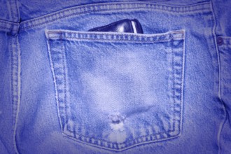 A Worn and tattered blue Jeans pocket. Carrying a wallet in your back pocket can hurt your back