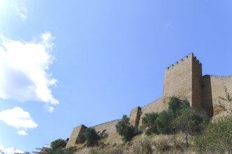 Ronda, malaga, spain Stone fortress wall and battlement under a bright blue sky, showing
