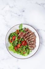 Fried tuna in sesame seeds, sliced on a plate, with fresh salad, on a white plate, homemade