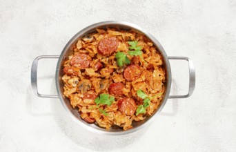 Polish dish bigos, in a stainless steel pan, stewed meat with cabbage, chorizo sausages, mushrooms,