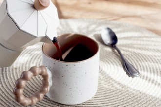 Pouring fresh coffee into a ceramic cup, geyser coffee maker, natural light, breakfast