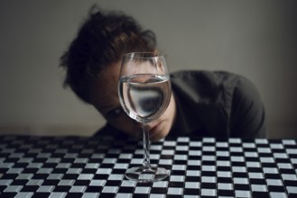 Woman's face behind a wine glass, with reflection in water