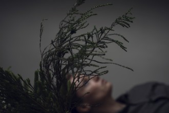 Woman holding ostrich with grasses, face covered