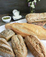 Various freshly baked artisanal breads and rolls presented on a white cloth on a rustic wooden