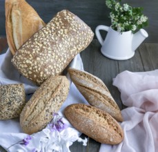 Artisanal bread loaves and rolls featuring various grains and seeds arranged on a white cloth,
