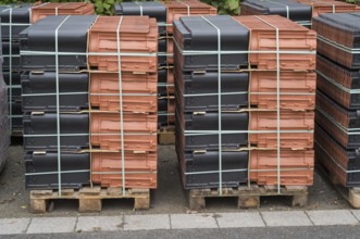 Borken, NRW, Germany, New terracotta and black roof tiles packaged on wooden pallets for
