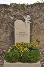 Children's grave with angel figure and beautiful floral decoration on a cemetery wall, Upper
