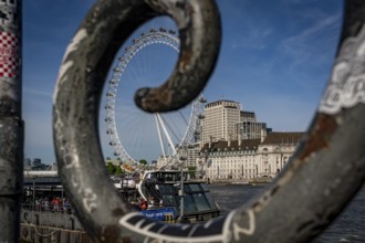 London, United Kingdom - 14 May 2025: The iconic London Eye framed by the railings along the Thames