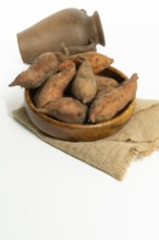 Freshly picked sweet potato in a wooden bowl with white background and copy-space