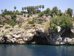 A panoramic view of a grotto with caves in the mountain cliffs jutting out from the azure and