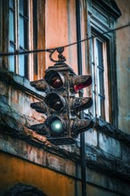 An old traffic light in front of a building shows green light