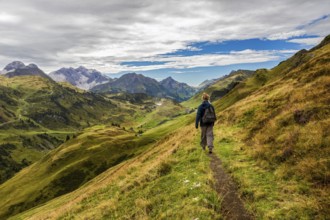 A hiker on a narrow path in the middle of a picturesque mountain landscape, Schröcken, Austria