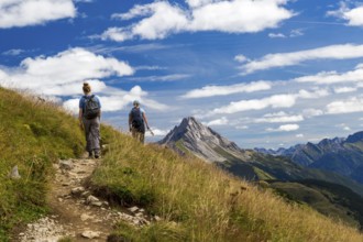 Two hikers on a trail in mountainous landscape under blue sky, Schröcken, Austria