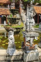 Guardian figures in front of an old well in Brahma Vihara Arama Buddha Banjar Buddhist monastery,