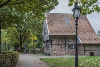 Quiet village scene with half-timbered house and lantern under old trees, a path leads through
