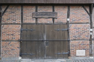Wooden and brick gate of a medieval half-timbered house with rustic sign, Münsterland, North