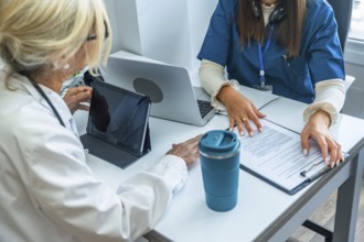Healthcare team reviewing digital tablet and medical records, discussing patient care plans and