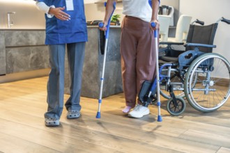 Healthcare professional assisting a patient learning to walk with crutches, providing support