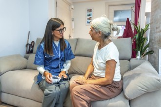 Healthcare professional checking blood pressure for an elderly woman during a home medical visit,
