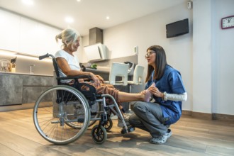 Healthcare professional assisting a senior woman in a wheelchair with foot and leg physical therapy