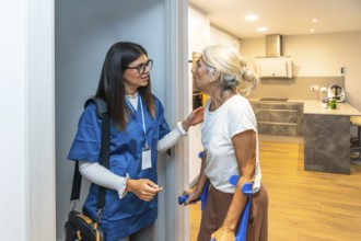 Caregiver wearing scrubs and carrying a medical bag assisting an elderly woman using crutches at