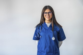 Female doctor in blue scrubs with stethoscope, smiling confidently at camera on white background,