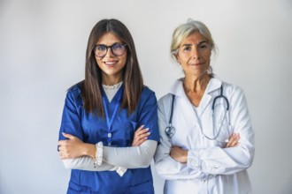 Two women healthcare professionals, a younger nurse in blue scrubs and an older doctor in a white