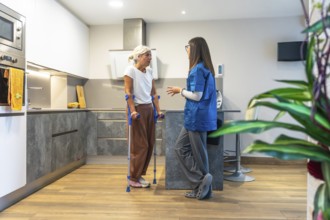Home caregiver interacting with a senior woman using crutches, providing support and advice for her