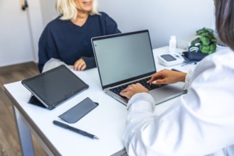 Doctor engaging in a medical consultation with a senior patient, typing health information and
