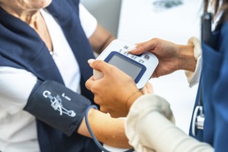 Healthcare professional checking a senior woman's blood pressure at home or in a clinic, focusing