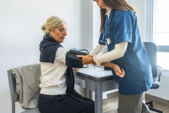 Healthcare professional checking a senior woman's blood pressure. Monitoring her health during a