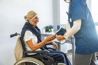 Medical professional checking a senior woman's blood pressure while she is sitting in a wheelchair,