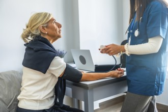 Medical professional monitoring and recording an elderly patient's blood pressure with a