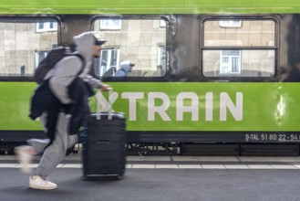 Flixtrain train on track 2 in Essen main station, passenger runs with luggage to reach his train,