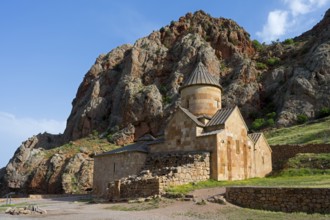 A stone church nestled in a rocky landscape with blue sky in the background, Noravank monastery,