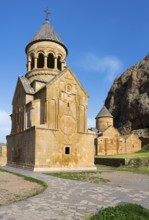 An ornate stone church with a paved path in the foreground and a blue sky ceiling, Noravank