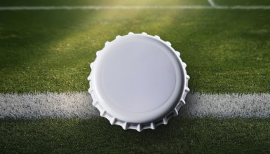 A white bottle cap placed on a soccer field's grass near a white line, symbolizing sports,