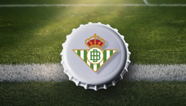 Bottle cap featuring the Real Betis logo placed on a football field, representing team pride and