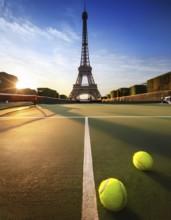 A tennis court with tennis balls and the Eiffel Tower in the background during sunset, symbolizing