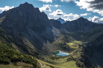 View from the Sallfelder Höhenweg hiking trail to Lache See and mountains of the Allgäu Alps, on