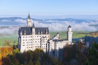 Majestic Neuschwanstein Castle overlooking spring-like valley with clouds and autumn trees,