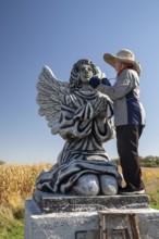 Chandler, Minnesota - Artist Primi Monteiga re-paints her concrete sculpture of an angel in the
